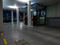 a empty room with the city lights on, a fire hydrant at the entrance and a large open door with a night view