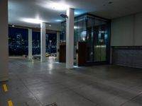 a empty room with the city lights on, a fire hydrant at the entrance and a large open door with a night view