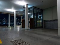 a empty room with the city lights on, a fire hydrant at the entrance and a large open door with a night view