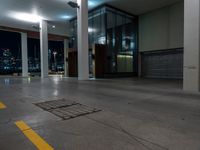 a empty room with the city lights on, a fire hydrant at the entrance and a large open door with a night view