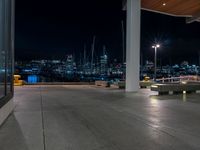 a large concrete deck with benches and a view of the city lights in the background