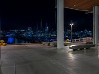 a large concrete deck with benches and a view of the city lights in the background