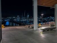 a large concrete deck with benches and a view of the city lights in the background