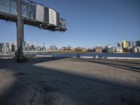 an empty parking lot next to the water in front of some tall buildings with a city view