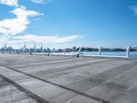 the sky is blue with white clouds in it and people are walking on the dock, along with two large buildings