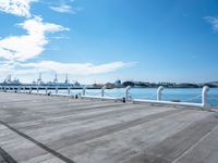 the sky is blue with white clouds in it and people are walking on the dock, along with two large buildings