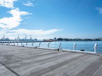 the sky is blue with white clouds in it and people are walking on the dock, along with two large buildings