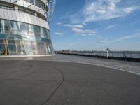 the ground is covered in asphalt and is next to an observation tower, with buildings reflected in the window windows