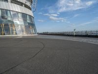 the ground is covered in asphalt and is next to an observation tower, with buildings reflected in the window windows