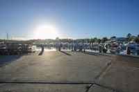 the sun shines on a marina and boats docked in a bay on the right