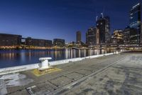 a large body of water surrounded by buildings at night time and lights on a pier