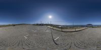 a fish eye lens that is reflecting the sun on the ground and some buildings in the background