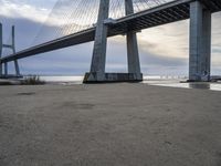 the big bridge is near the water and the sand is empty with no one around it