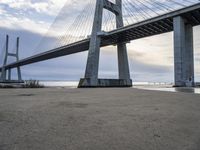 the big bridge is near the water and the sand is empty with no one around it