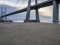 the big bridge is near the water and the sand is empty with no one around it