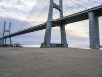 the big bridge is near the water and the sand is empty with no one around it