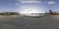 an oval shaped panorama with the sun setting on the water and a bridge in the distance