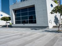 a skateboarder rides past a concrete building with lots of windows on the outside