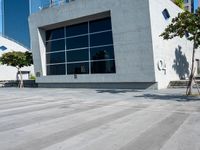 a skateboarder rides past a concrete building with lots of windows on the outside