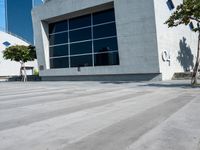 a skateboarder rides past a concrete building with lots of windows on the outside