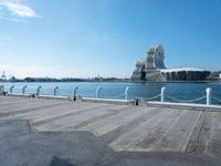 a view of some people sitting on a bench by water and buildings with a view