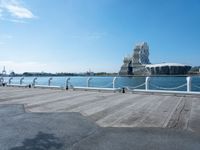 a view of some people sitting on a bench by water and buildings with a view