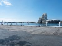 a view of some people sitting on a bench by water and buildings with a view