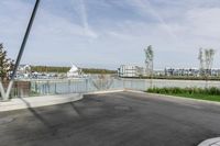 a parking lot with a fence near the water and buildings in the background that includes several boats