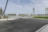 a parking lot with a fence near the water and buildings in the background that includes several boats