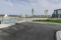 a parking lot with a fence near the water and buildings in the background that includes several boats