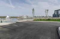 a parking lot with a fence near the water and buildings in the background that includes several boats