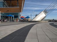 this is an outdoor place that contains tables and umbrellas and a sculpture on a high platform