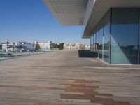 wooden floors in front of a glass window overlooking a city and water feature on the roof