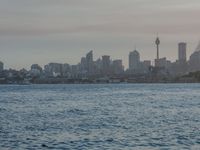 an ocean view of a skyline and skyscrapers at sunset in the background, including an airplane