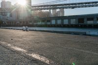 a couple of children and their skateboards near the water under a bridge that spans across a city street