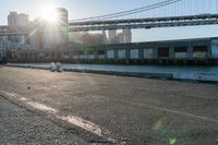 a couple of children and their skateboards near the water under a bridge that spans across a city street