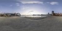 an oval shaped panorama with the sun setting on the water and a bridge in the distance