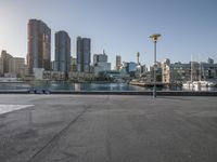 an empty parking lot in the city with boats docked on it's water way