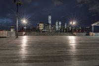 a view of new york city skyline at night from pier on the hudson river side