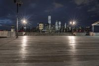 a view of new york city skyline at night from pier on the hudson river side