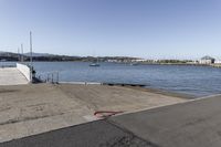 the boardwalk is leading towards the water to a pier next to some boats on the beach