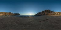 three motorcycles are parked on the beach near the water and cliffs at sunset time in a fish eye photo