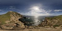 a view of the sea, and cliffs on a cloudy day with sun rays coming over the ocean