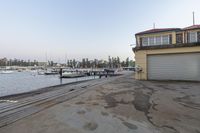 the dock has many boats on it and is empty from view of water, and in front of an apartment building