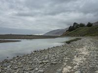 a rock shoreline with an overcast sky in the background and trees in the distance