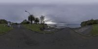 the view of an intersection with a street and a body of water in the background