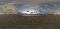 a fish eye view of the ocean and sand with a cloud in the background in a panoramic style