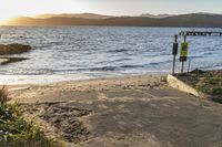 an old gate is on the beach as the sun sets behind it, in front of an ocean