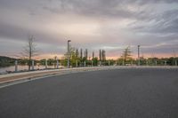 a winding road on a cloudy evening near the water's edge and a street light