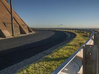 a very long stretch of road in the country with grass on either side and an overhang behind